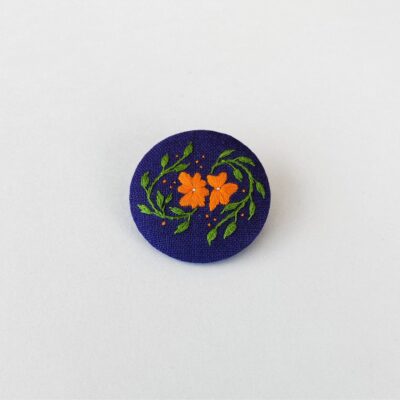 Broche brodée main avec motif fleurs oranges sur tissu en lin