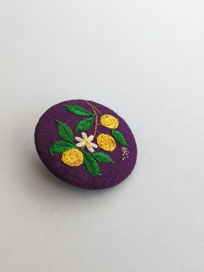 Détail broche textile avec motif citrons brodé à l'aiguille