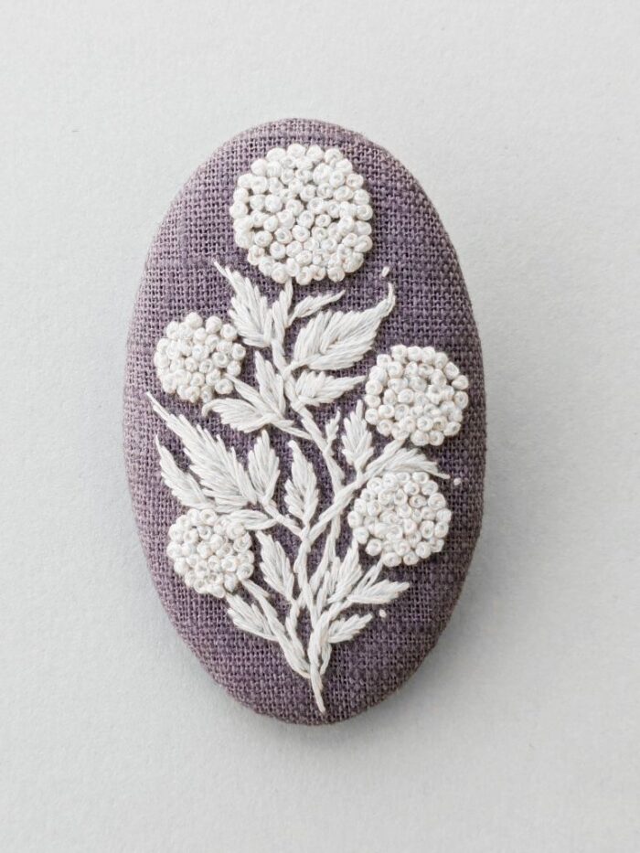 Détail broche textile avec broderie réalisée à l'aiguille