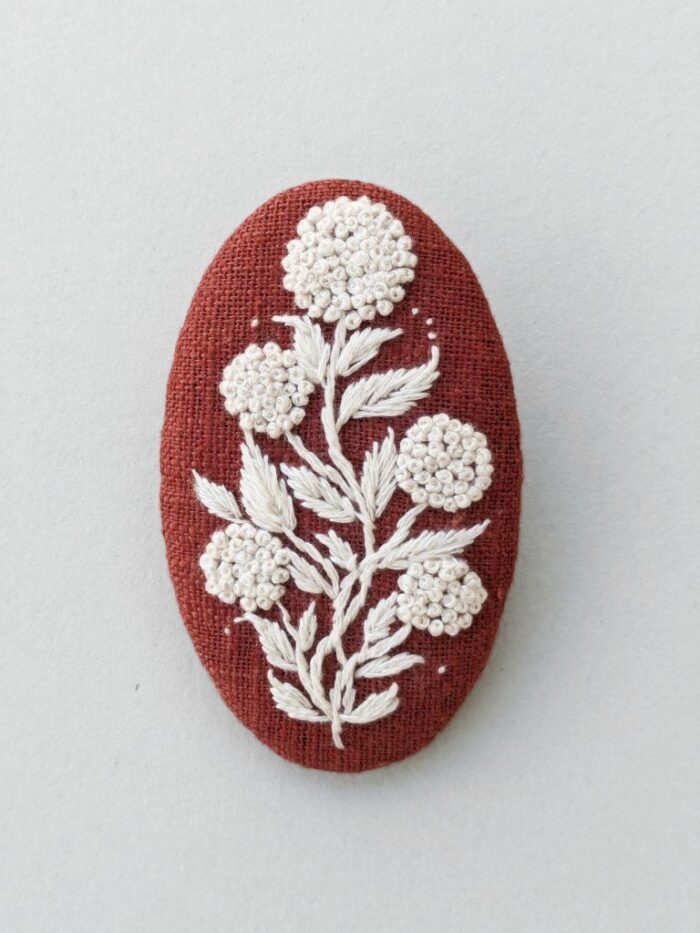 Détail broche textile avec motif fleur brodé à l'aiguille