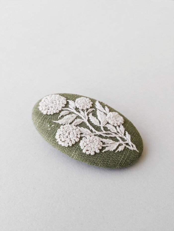 Broche textile avec motif fleur brodé à l'aiguille