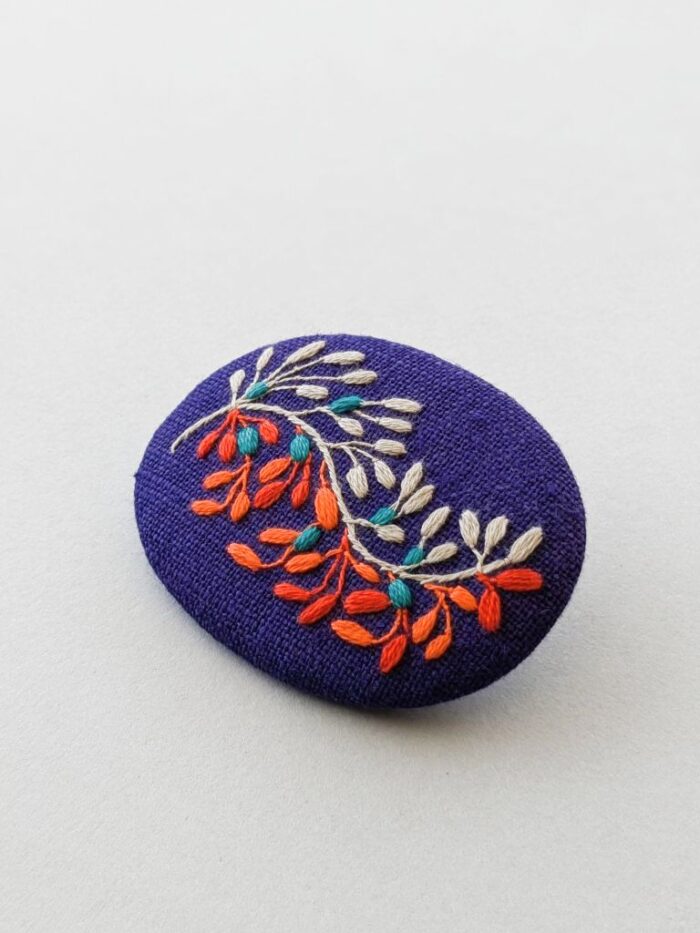 Détail broche en lin avec broderie fleur réalisée à l'aiguille